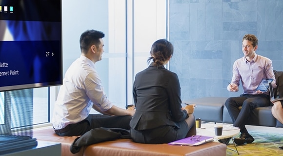 A group of people gathered around a Samsung SMART Signage at a hotel lobby