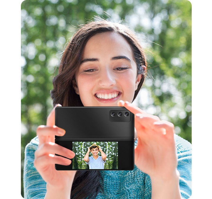 Ženska, ki z razprtim Galaxy Z Fold2 mobilnim telefonom v roki glavno kamero obrne proti vam. Na zunanjem naslovu vidimo predogled vaše fotografije, kar prikazuje možnost preprostega preverjanja fotografij v realnem času s funkcijo Dvojnega predogleda.