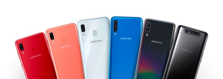 ตรงกลางของหน้าจอมีโทรศัพท์ซีรีส์ Galaxy A ของ Samsung 6 เครื่องวางอยู่ในสีต่าง ๆ เรียงจากซ้ายไปขวาตามนี้ โทรศัพท์เครื่องที่ 1 เป็นสีแดงเข้ม, โทรศัพท์เครื่องที่ 2 เป็นสีแอปริคอตออเรนจ์อ่อน, โทรศัพท์เครื่องที่ 3 เป็นสีเงินมันวาว, โทรศัพท์เครื่องที่ 4 เป็นสีโคบอลต์บลู, โทรศัพท์เครื่องที่ 5 เป็นสีดำหนังแก้ว, โทรศัพท์เครื่องที่ 6 เป็นสีดำด้าน