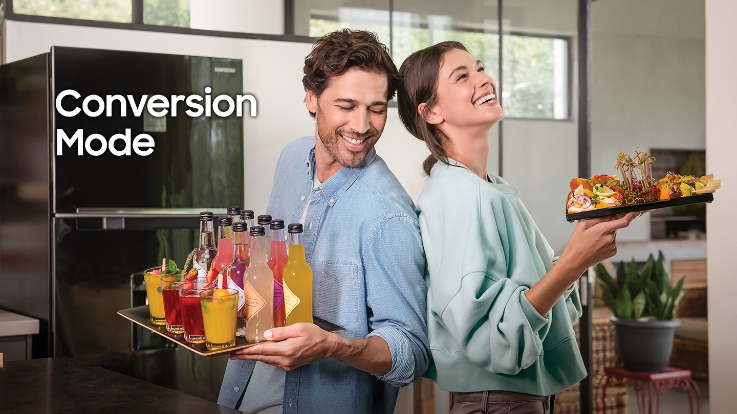 This image explains conversion mode of Samsung Top mounted refrigerator. In it, a couple standing in front of the image, and holding a tray that has party beverages on it.
