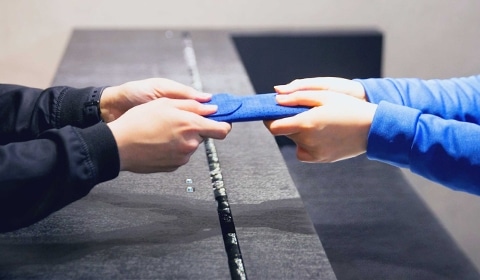 Closeup of the hands of a Galaxy Consultant handing a repaired phone in a case to the hands of a client across the counter
