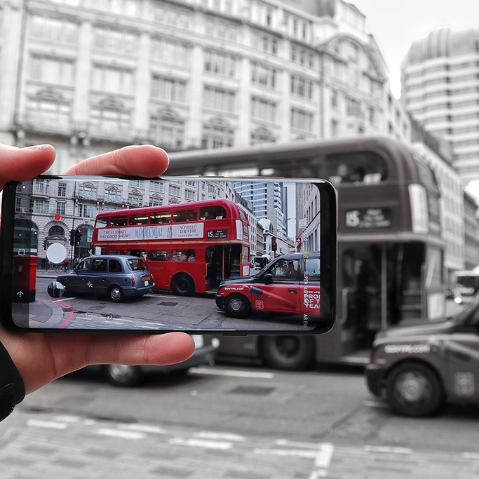 A closeup of someone taking a photo of a London bus