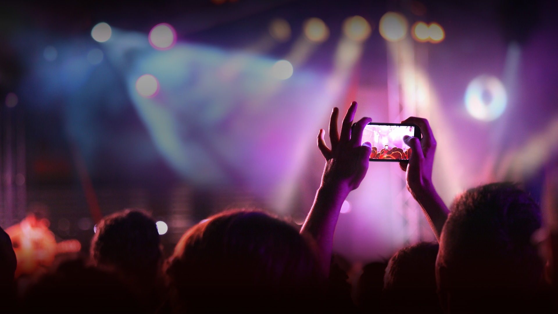 O fotografie a unei persoane care face o poză cu un telefon Galaxy S9 ținut în mână la un concert live.