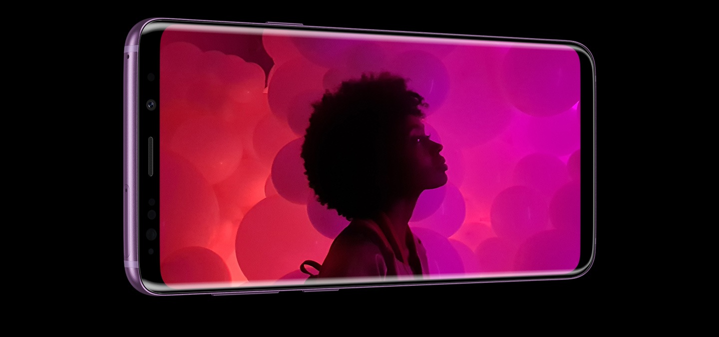 O fotografie portret a unei femei care se uită la ceva în depărtare, făcută cu funcția de fotografiere în condiții de luminozitate scăzută a telefonului Samsung Galaxy S9.