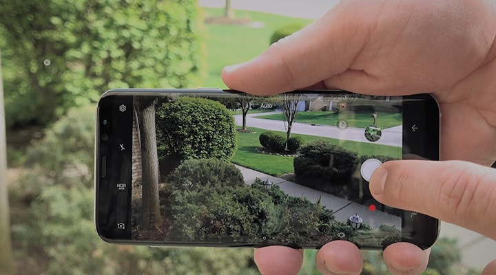 Fă clic pentru a reda un clip video cu recenzii O imagine ținând Galaxy S8 Midnight Black în mâna dreaptă cu camera pornită.