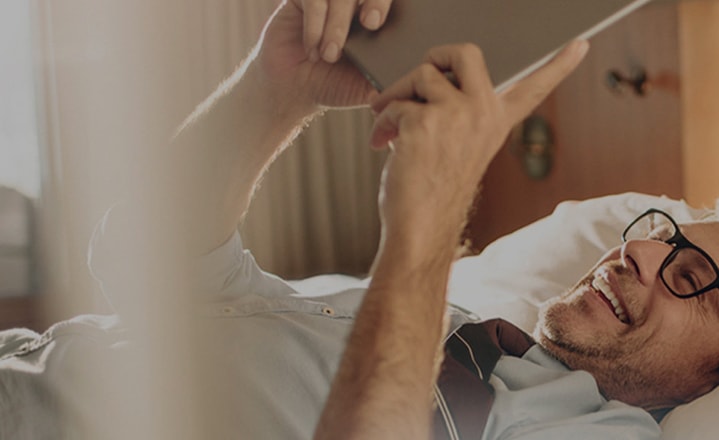 A man lying on a bed with Galaxy Tab S5e in his hands, representing tech gift ideas for Father's day