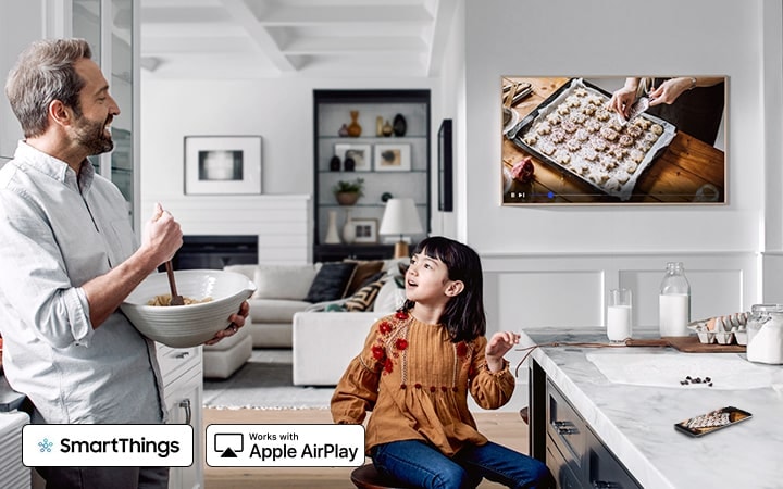 Father and daughter watch a cooking video on The Frame that mirrors the phone screen by connecting the phone to the TV.