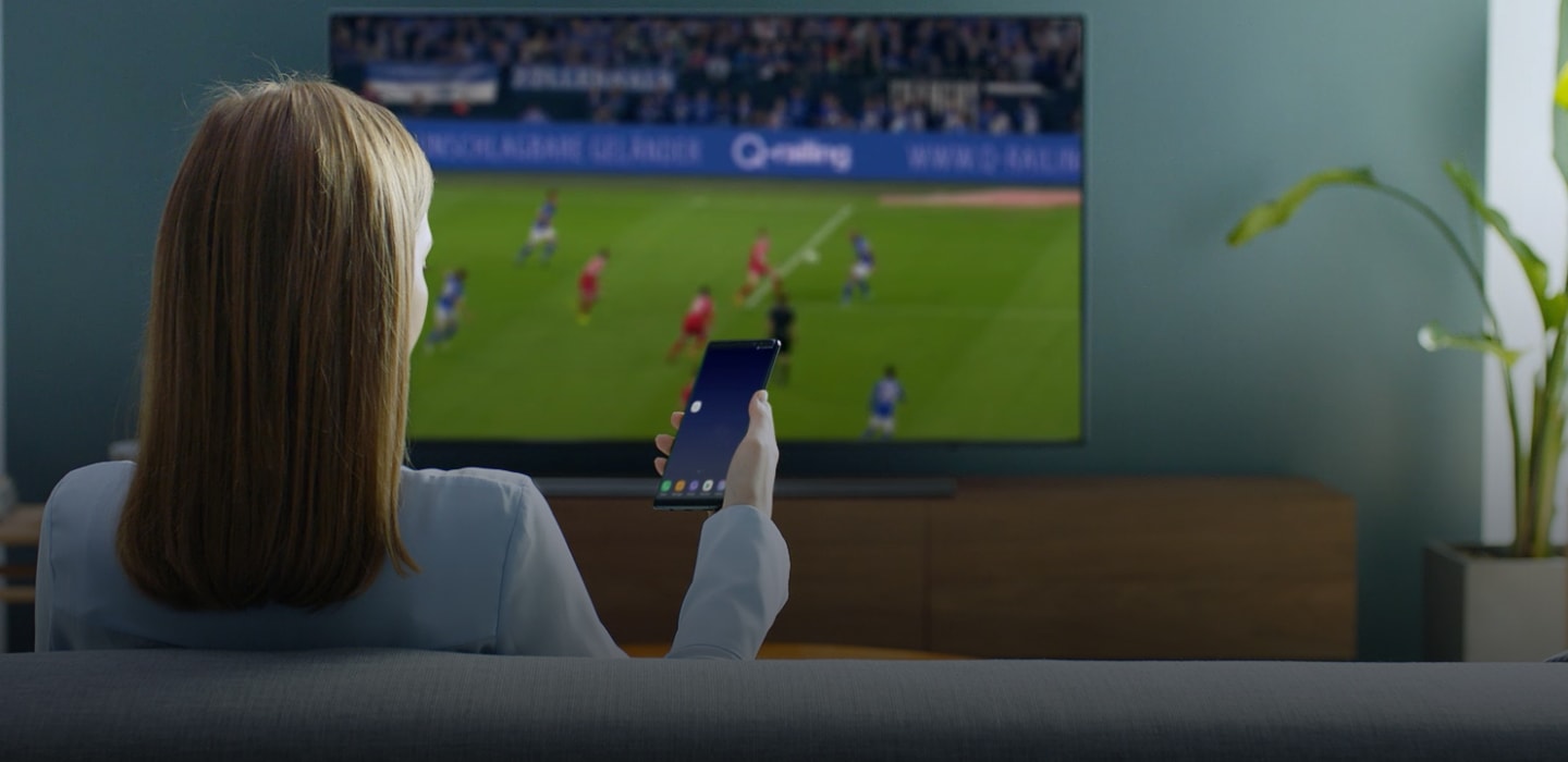 Use your mobile Woman watching sport on Smart TV, controlling with her mobile