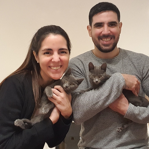 Man and woman holding cats their arms, smiling