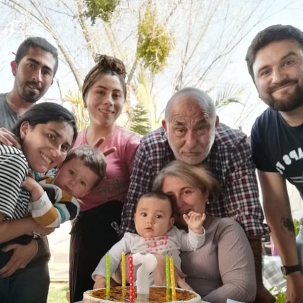 Family gathered around the table smiling while celebrating youngest child's birthday
