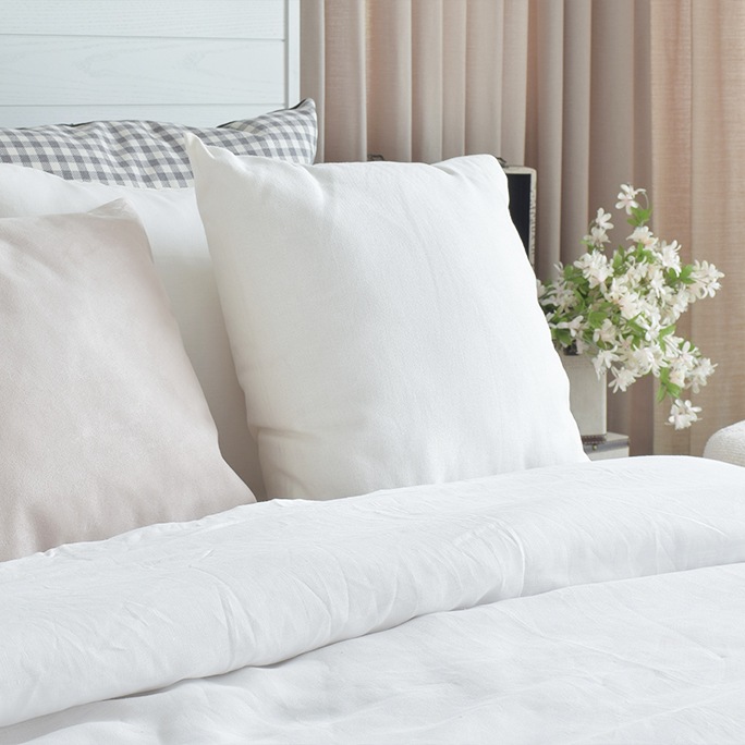 침대 위에 하얀 베개와 이불이 깔끔하게 정돈되어 있습니다.