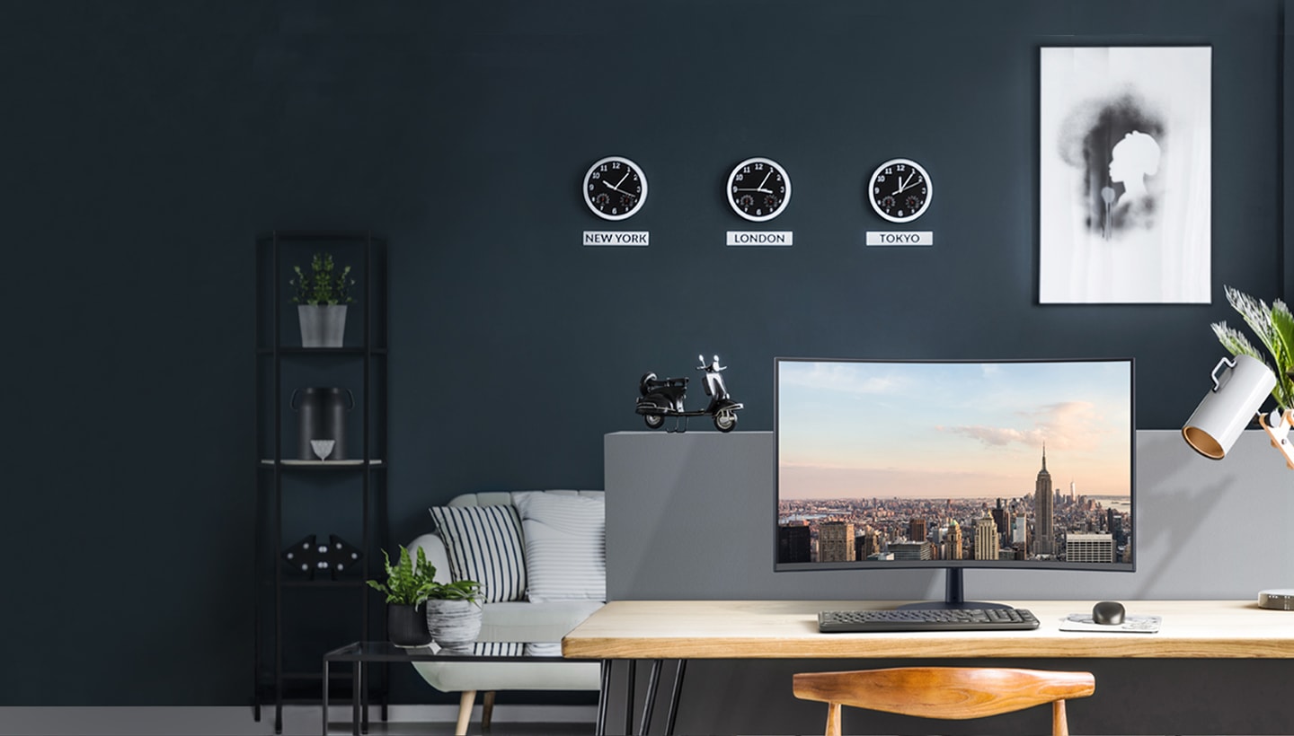 책상 위에 삼성 모니터가 있습니다. 벽에는 뉴욕, 런던, 도쿄의 시간을 나타내는 시계가 걸려 있습니다.