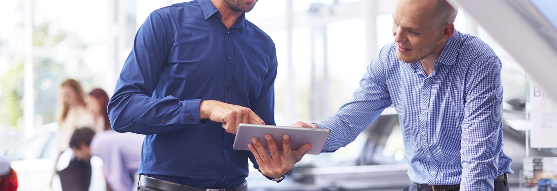 An image showing two men wearing blue shirts. They are looking at the Galaxy Book 10.6’s screen. One man is holding the device and pointing at it, while the other also pointing at the device’s screen.