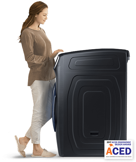 A woman stands by the washing machine. She appears to be loading laundry.