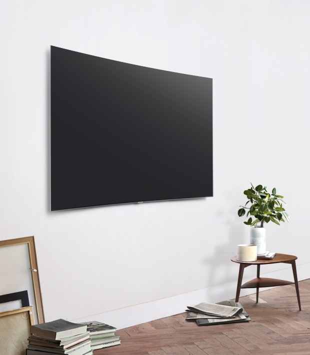 TV QLED treo trên tường màu trắng trong phòng khách, và chiếc bàn gỗ được đặt dưới TV.