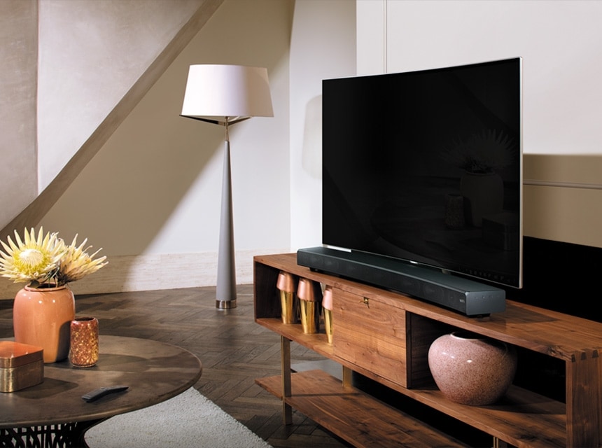 Nội thất phòng khách theo phong cách gỗ. TV QLED và loa Soundbar đặt trên bàn gỗ nâu.