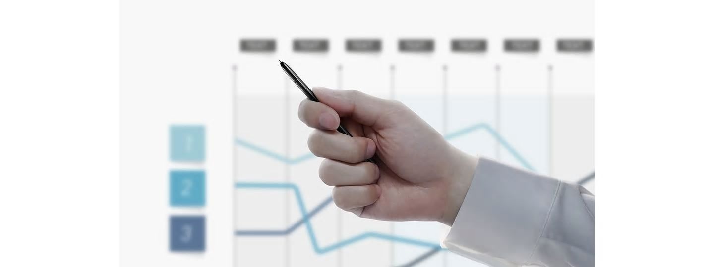 Simulated image of a person holding the S Pen with a presentation in the back showing a line graph. After the person clicks the S Pen button, the presentation slide switches to another graph.