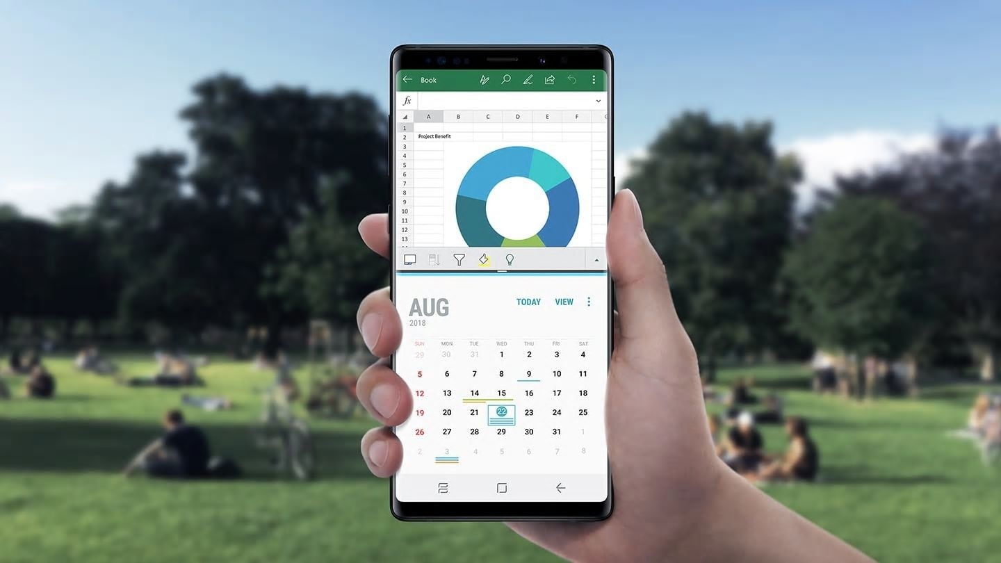 Image of person holding Galaxy Note9 in front of a busy street scene with a spreadsheet and the Calendar app onscreen, demonstrating multitasking capabilities