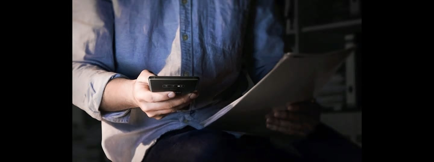 Image of a man holding Galaxy Note9 in a low light environment at night