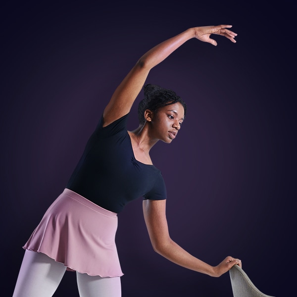 A woman is stretching out her right legs in a ballet pose.