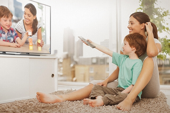 2 people are watching photos on Smart TV; the boy is conroling the One Remote Control.