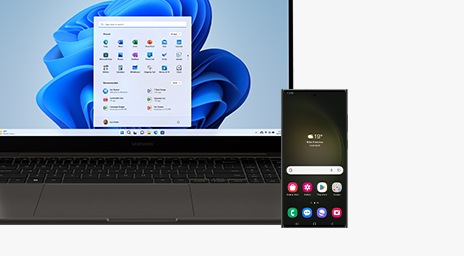 A graphite Galaxy Book3 Ultra is opened and facing forward with the MS Home Screen shown onscreen. A Galaxy S23 Ultra device is placed in front of the laptop with the Home Screen shown onscreen.