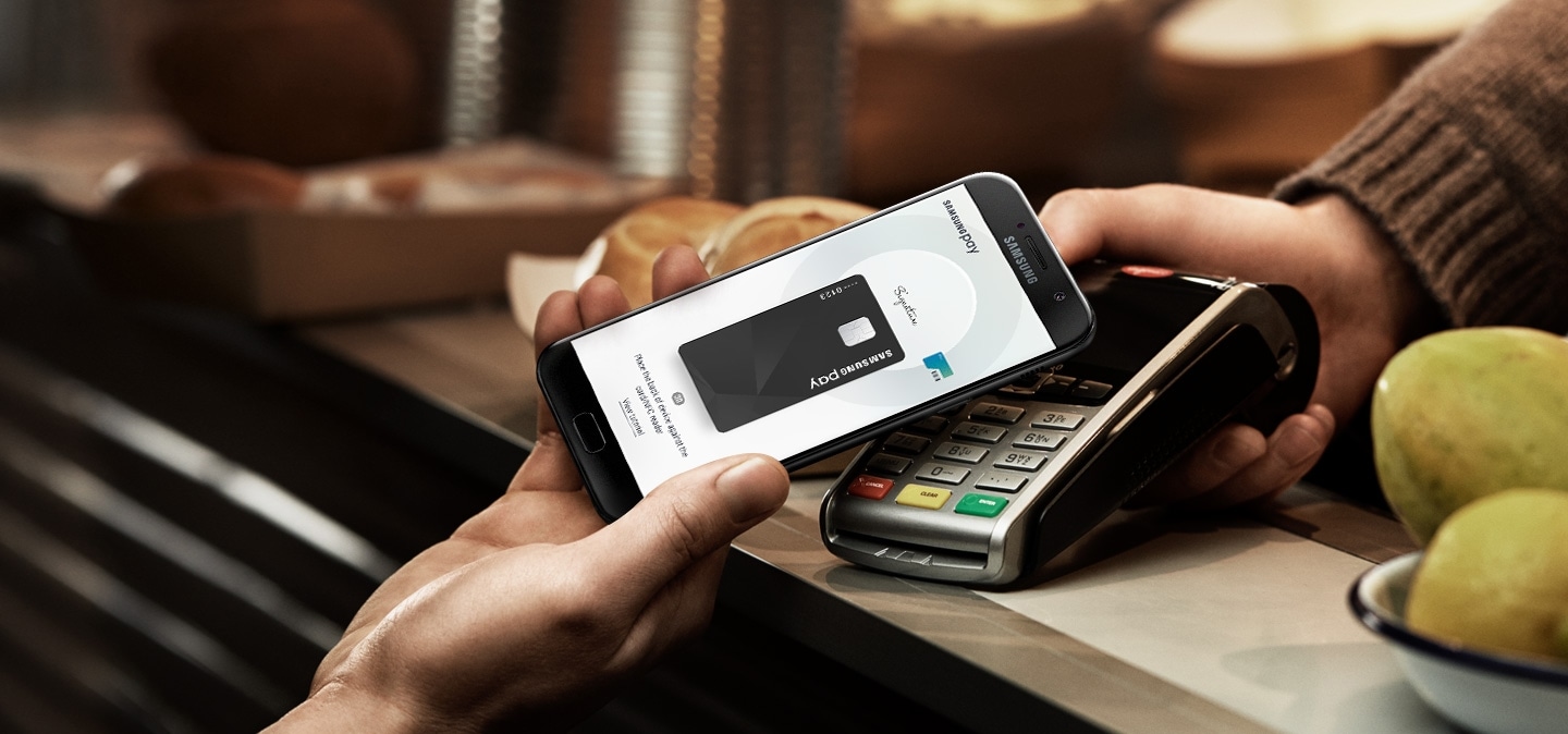Image displays the Galaxy A7 (2017) completing a transaction with Samsung Pay.