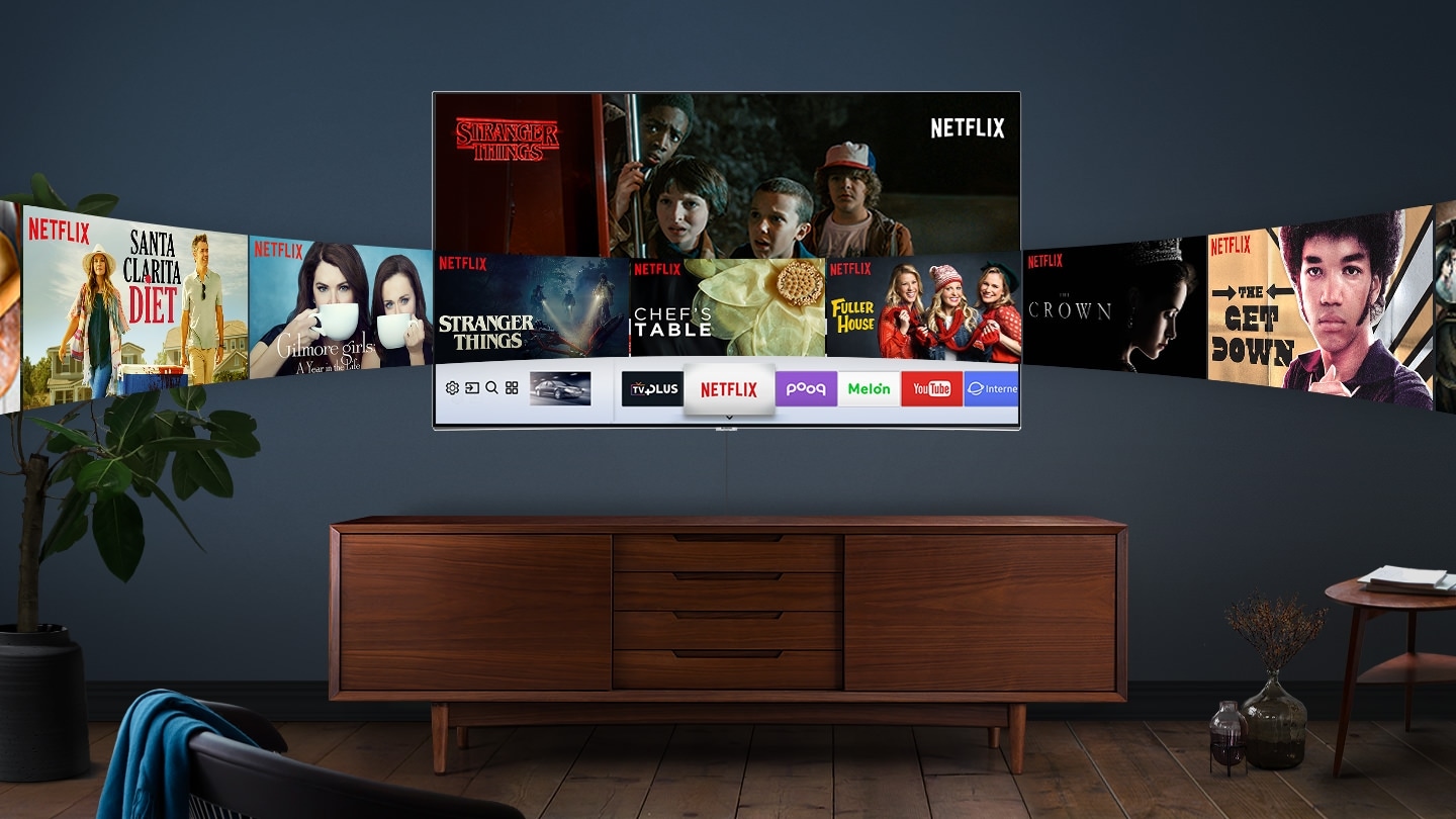 중앙 벽에 QLED TV가 걸려있으며 화면안에는 NETFLIX 이미지와 좌우측으로 NETFLIX에서 방영하는 드라마 및 영화들의 이미지들이 QLED TV를 기준으로 유선형으로 이루어져 있습니다. QLED TV앞쪽에는 작은 선반과 좌측엔 화분, 우측에는 미니 테이블이 있으며 정면에는 의자가 놓여져 있습니다.