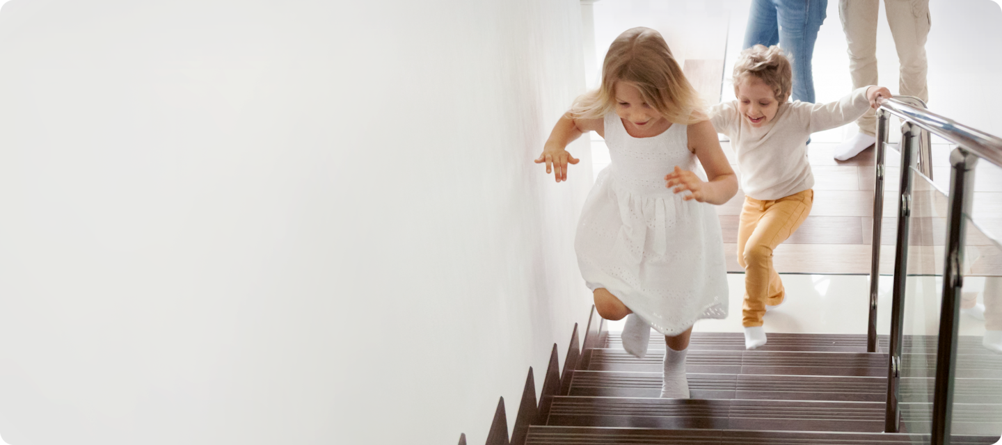 두 아이가 해맑은 웃음과 함께 계단을 뛰어 오르고 있습니다.