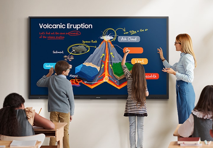 수업이 진행중인 교실의 모습입니다. 벽면에 설치된 전자칠판 WAF 시리즈를 통해 교과내용이 보여지고 있으며, 두명의 어린이가 앞으로 나와 전자칠판에 듀얼펜을 이용해 내용을 쓰고 있는 모습입니다.