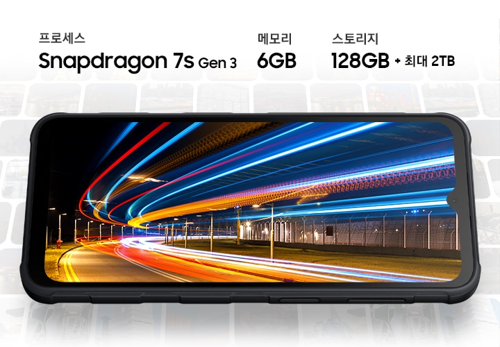 갤럭시 엑스커버7 프로가 전면을 드러내며 가로 모드로 놓여져 있습니다. 화면에는 빠른 속도를 연출하기 위해 밝은 네온 블루와 오렌지 색상의 모션 라인이 지나가는 모습이 표시되어 있습니다. 화면에는 프로세서 스냅드래곤 7s Gen3, 메로리 6GB, 저장 공간 128GB+최대 2TB라는 텍스트가 있습니다.