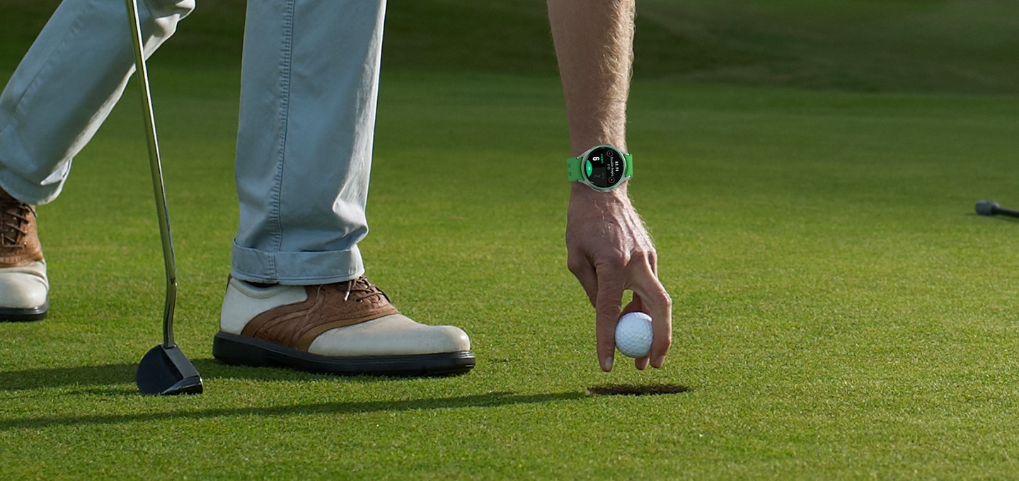 갤럭시 워치6 클래식 골프 에디션을 착용한 사람이 홀에서 공을 줍는 모습이 보입니다.