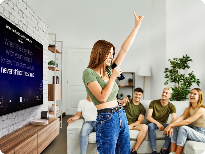 여성이 TV 노래방 기능을 활용하여 노래를 부르고 있습니다.