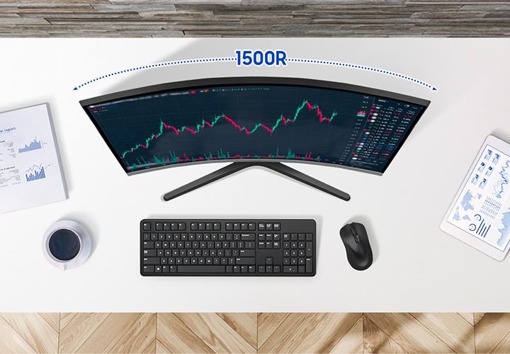 책상을 위에서 내려다보는 모습이고, 책상 위에는 그래프 자료, 커피, 키보드, 마우스, 태블릿pc가 올려져 있습니다. 모니터 화면에는 주식 그래프가 보입니다.