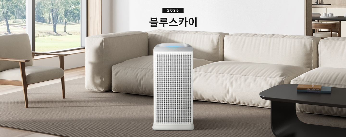 베이지 톤의 거실이 배경으로 보이고 있습니다. 이미지 중간 부분에는 블루스카이의 정면 이미지가 보이며, 이미지 상단 부분에는 2025 블루스카이 텍스트가 보이고 있습니다. 제품 이미지 왼쪽 부분에는 패브릭으로 된 1인용 의자와 창문 밖으로 나무가 보이고 있고 제품 이미지 오른쪽 부분에는 패브릭으로 된 소파와 블랙 색상의 테이블이 놓여 있습니다.