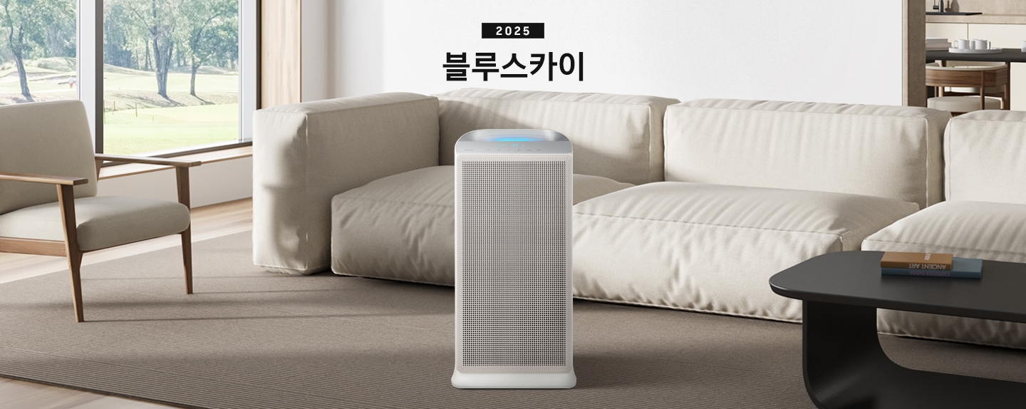 베이지 톤의 거실이 배경으로 보이고 있습니다. 이미지 중간 부분에는 블루스카이의 정면 이미지가 보이며, 이미지 상단 부분에는 2025 블루스카이 텍스트가 보이고 있습니다. 제품 이미지 왼쪽 부분에는 패브릭으로 된 1인용 의자와 창문 밖으로 나무가 보이고 있고 제품 이미지 오른쪽 부분에는 패브릭으로 된 소파와 블랙 색상의 테이블이 놓여 있습니다.