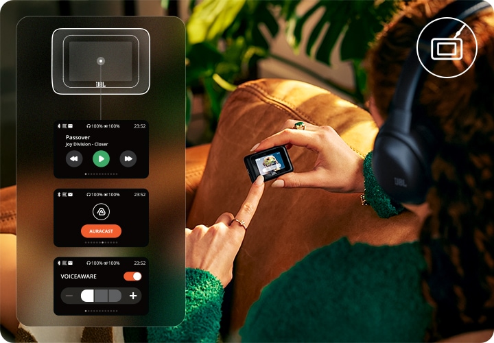 헤드폰을 착용한 여성이 소파에 앉아 트랜스미터를 보고 있습니다. 왼쪽에는 트랜스미터로 제어가능한 화면이 보입니다.