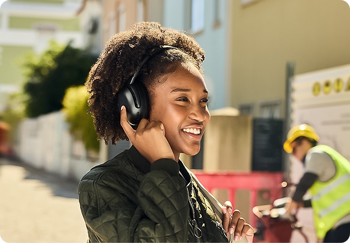 헤드폰을 착용한 여성이 오른손 검지손가락으로 헤드폰을 만지고 있습니다.