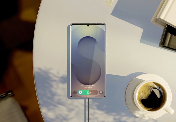 원형 탁자에 놓인 마그넷 무선 충전기가 부착된 스마트폰과 커피잔, 책들이 탑뷰로 보이고 있습니다.