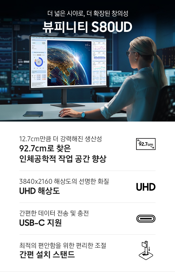 여성이 모니터를 응시하며 작업을 하고 있는 모습입니다. 모니터에는 지구모양과 다양한 그래프가 있습니다.