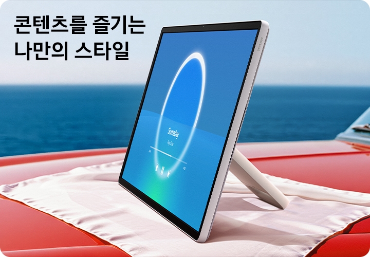 붉은 색 자동차 위에 흰색 보자기가 깔려 있습니다. 그 위에 스탠드에 분리된 The Movingstyle이 놓여 있습니다. 좌측 상단에는 '콘텐츠를 증기는 나만의 스타일'이라는 문구가 기재되어 있습니다.