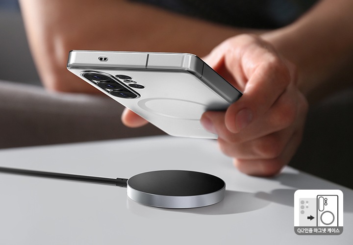 탁자에 마그넷 무선 충전기가 놓여있고, 한 사람이 스마트폰을 들고 충전기에 가깝게 들고 있습니다.