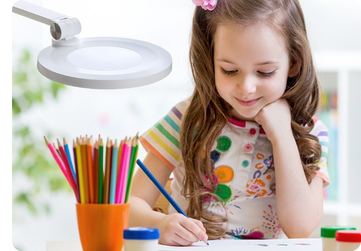 LED조명이 여자아이가 파란색 색연필로 종이에 작업하는 부분을 비추고 있으며, 책상 위에는  물감 여러개와 연필 꽂이에 다양한 색연필 여러개가 꽂혀 있는 실제 사용환경을 보여주는 연출된 이미지 입니다.