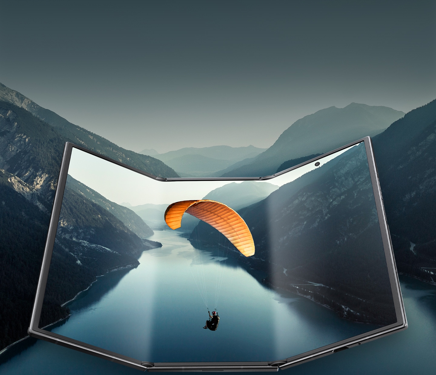 갤럭시 Z 트라이폴드가 거의 펼쳐진 상태로 넓은 메인 디스플레이가 나타납니다. 디스플레이에 등장한 풍경 이미지가 기기의 경계를 넘어 이어지며, 영화같은 장면을 강조합니다.