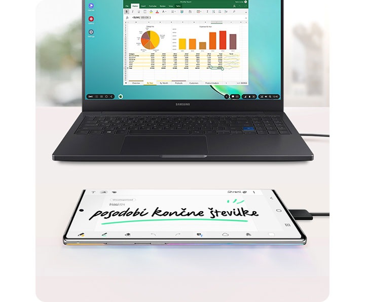 Samsung prenosnik s preglednico in grafi na zaslonu ter Galaxy Note10+ mobilni telefon, povezan preko USB kabla in z beležko na izključenem zaslonu.