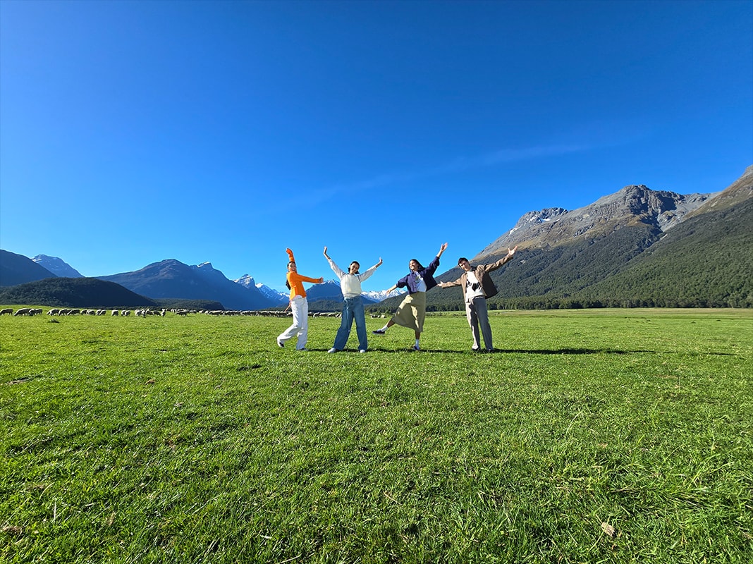 A photo of an open field and mountains with figures near the horizon taken at 0.6x zoom.