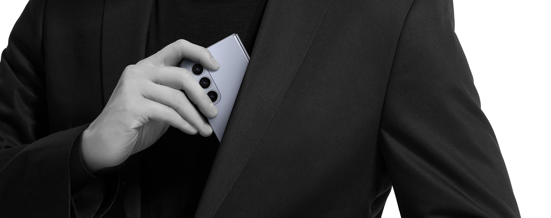 A folded Galaxy Z Fold5 is removed from the inner chest pocket of a blazer.