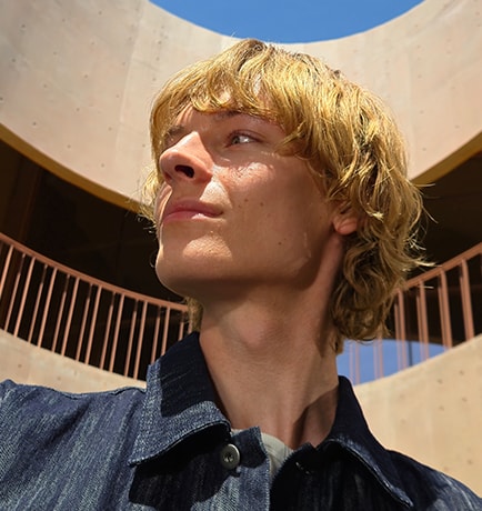 A 50 megapixel photo of a man against the backdrop of a building shows rich detail and color. When cropped in closer, details remain clear.