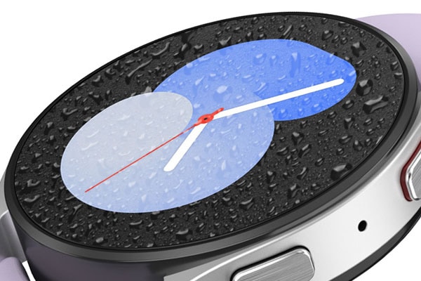 A Silver Galaxy Watch5 is displayed with a band. The watch face has water droplets on the surface, and shows one of the designs that display the time as ‘5’ in a gradient blue color.