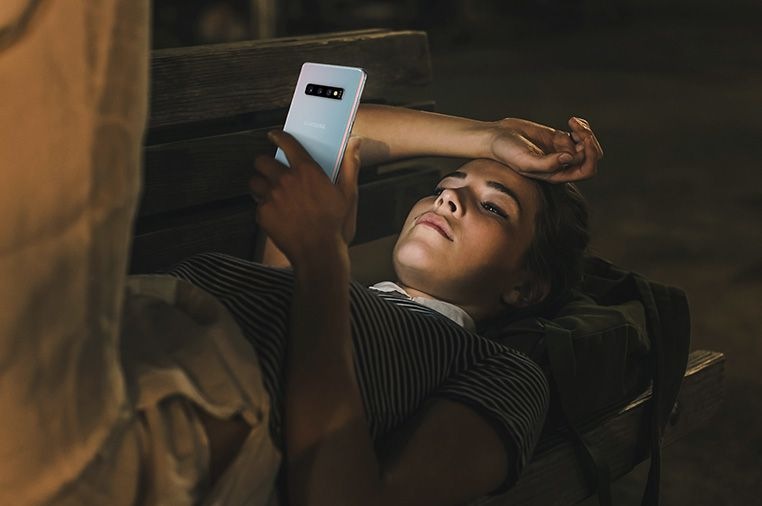 Image d'une femme allongée sur un banc la nuit à l'aide du Galaxy S10 plus.